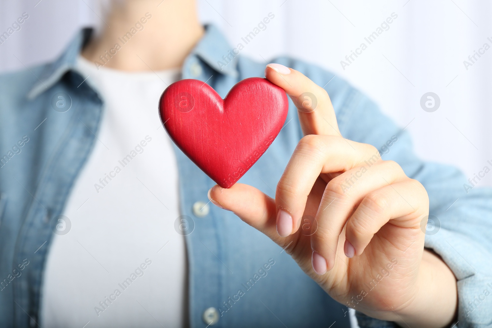 Photo of Woman holding red heart on light background, closeup