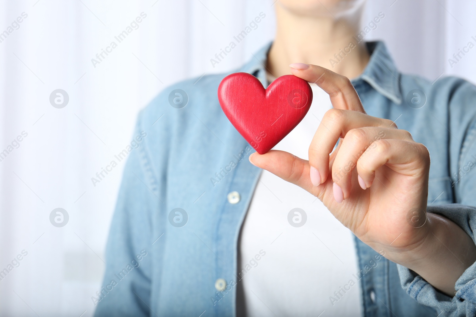 Photo of Woman holding red heart on light background, closeup