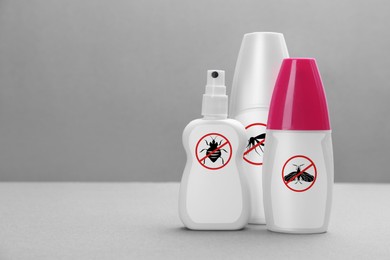 Image of Different insect repellents in spray bottles on grey background, space for text