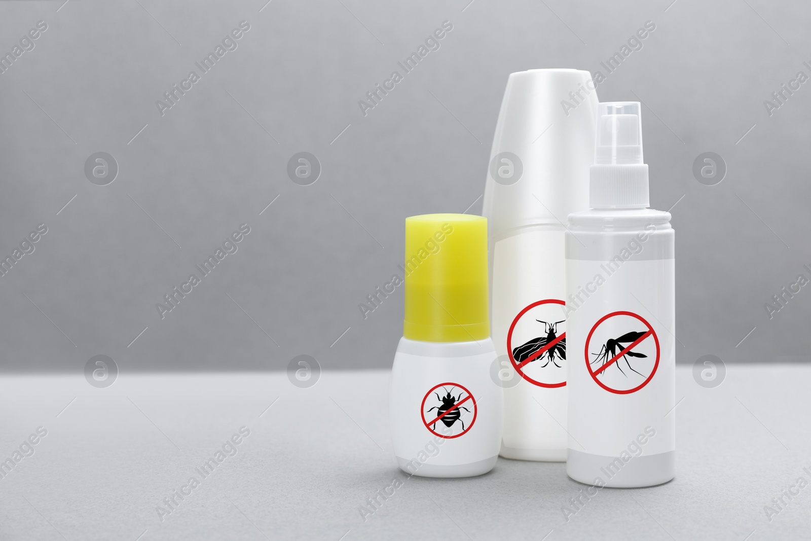 Image of Different insect repellents in spray bottles on grey background, space for text