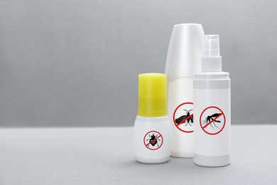 Image of Different insect repellents in spray bottles on grey background, space for text