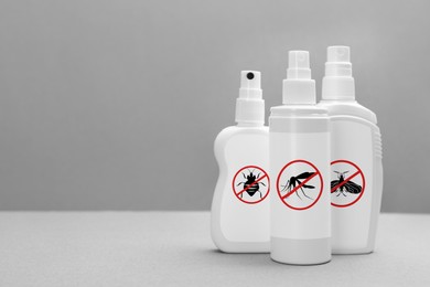 Image of Different insect repellents in spray bottles on grey background, space for text