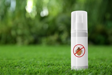 Insect repellent in spray bottle on green grass outdoors. Space for text