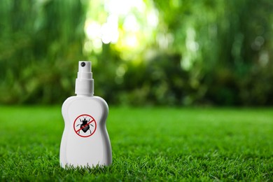 Insect repellent in spray bottle on green grass outdoors. Space for text