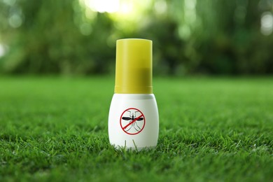 Image of Mosquito spray on green grass outdoors. Insect repellent