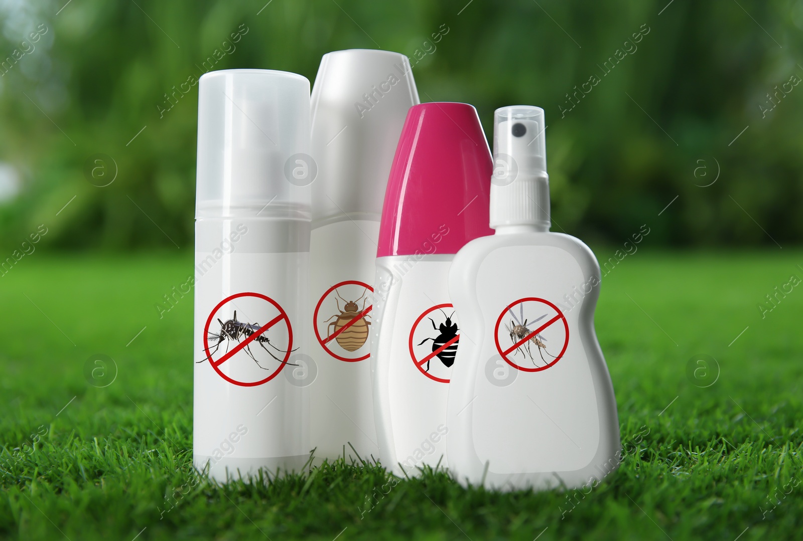 Image of Different insect repellents in spray bottles on green grass outdoors