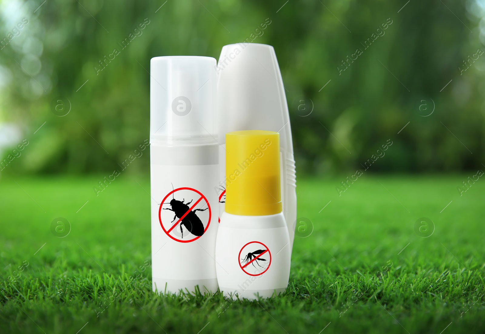 Image of Different insect repellents in spray bottles on green grass outdoors