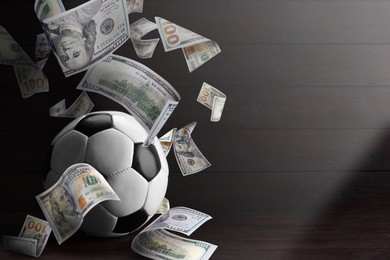 Image of Soccer ball under money rain on dark background, space for text