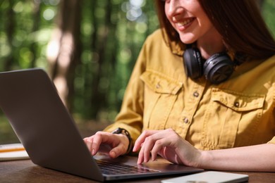 Photo of Smiling freelancer working with laptop at table outdoors, closeup. Remote job