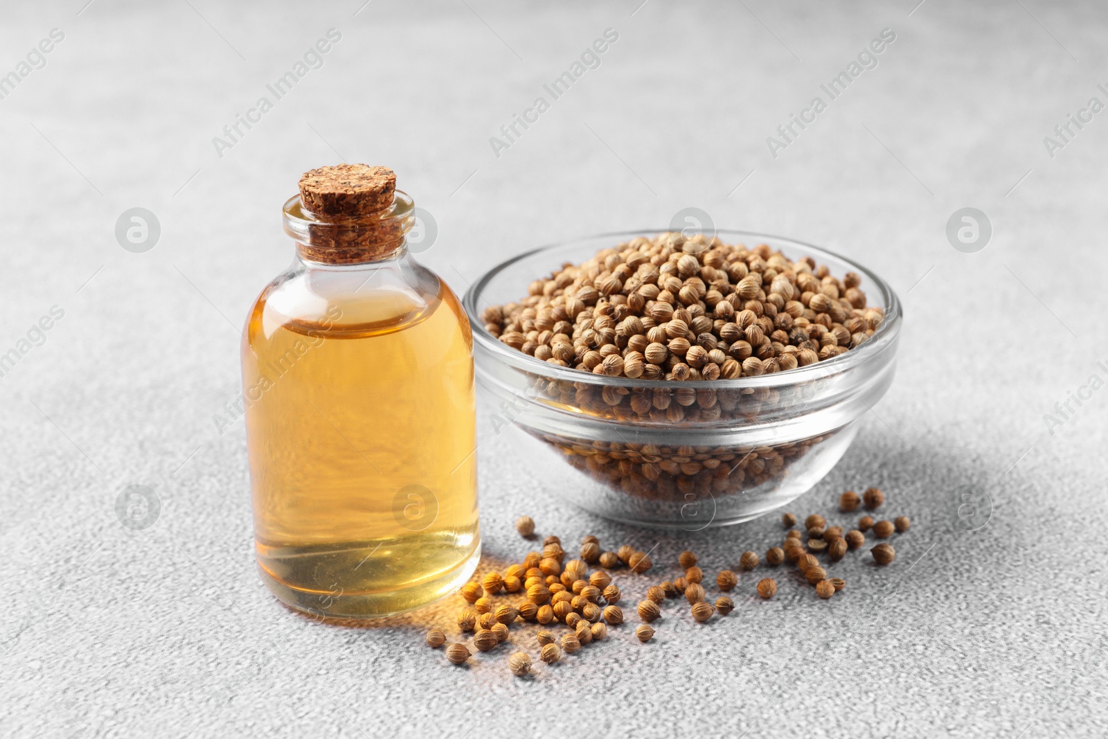 Photo of Coriander essential oil and seeds on grey table