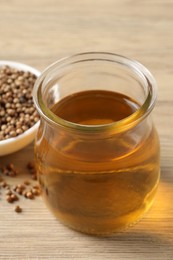 Coriander oil in glass jar and seeds on wooden table