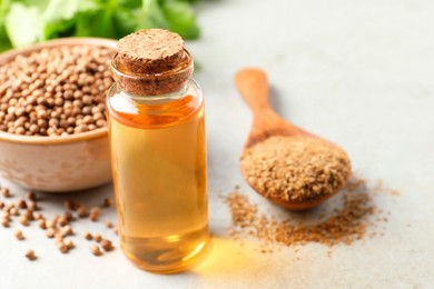 Photo of Coriander essential oil, powder and seeds on light grey table