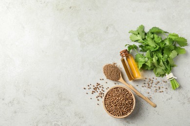 Photo of Coriander essential oil, powder, seeds and green leaves on light grey table, flat lay. Space for text