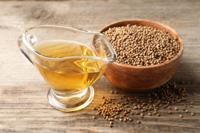 Dried coriander seeds in bowl and oil on wooden table