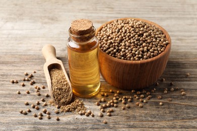 Photo of Coriander essential oil, powder and seeds on wooden table