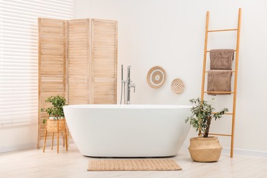 Photo of Folding screen, bathtub and green houseplants in bathroom