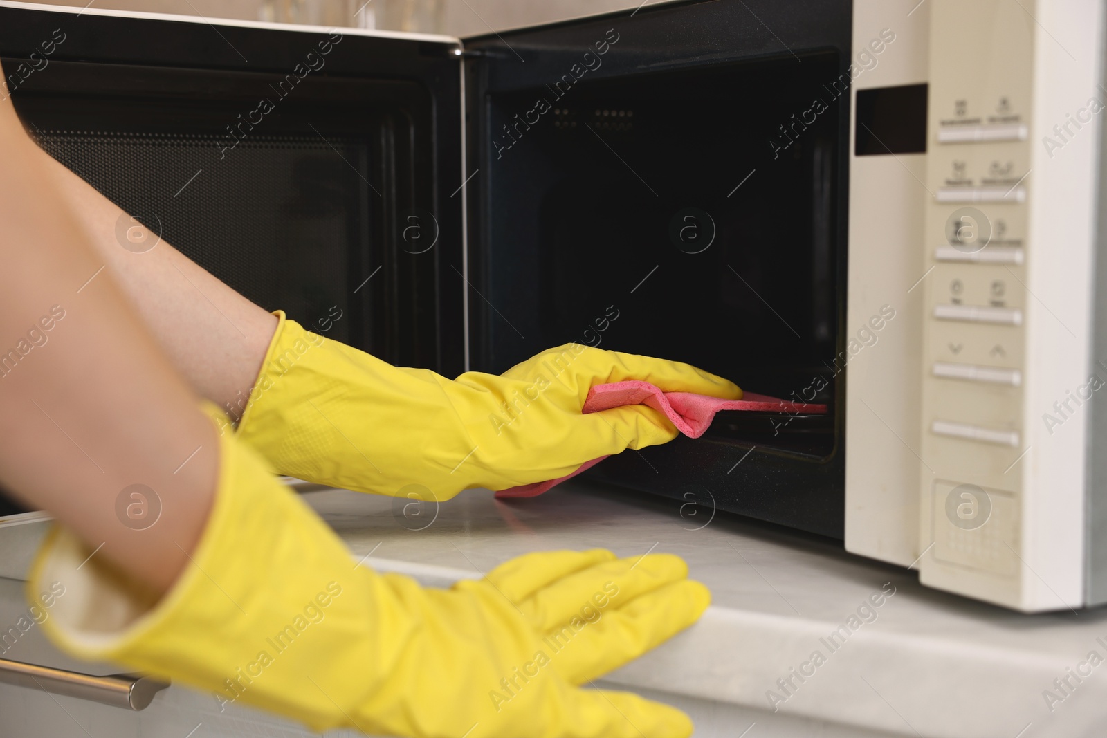 Photo of Professional janitor cleaning microwave oven in kitchen, closeup