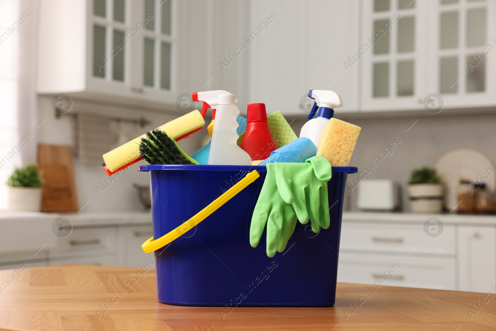 Photo of Cleaning service. Bucket with supplies on table in kitchen