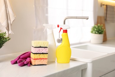 Cleaning service. Detergents, sponges and gloves on table in kitchen