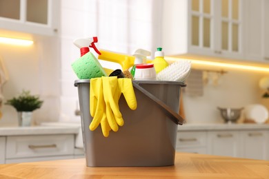 Photo of Cleaning service. Bucket with supplies on table in kitchen