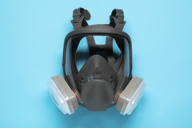 One full face respirator on light blue background, top view