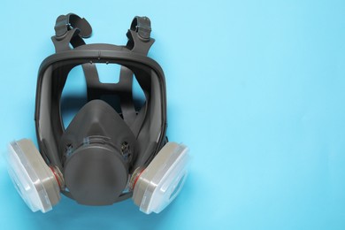 One full face respirator on light blue background, top view. Space for text