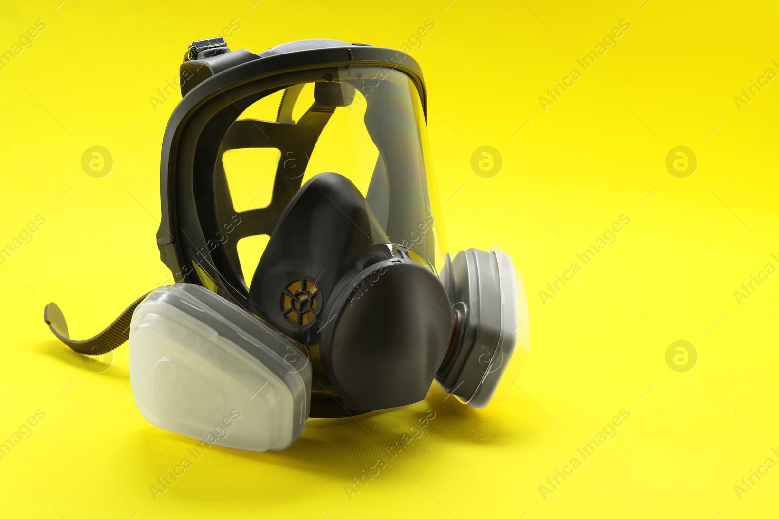 Photo of One full face respirator on yellow background, closeup. Space for text