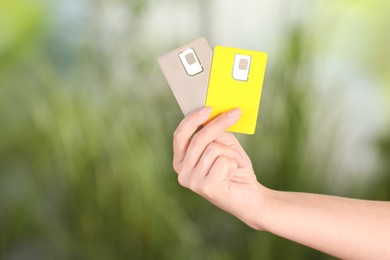 Photo of Woman holding SIM cards on blurred background, closeup. Space for text