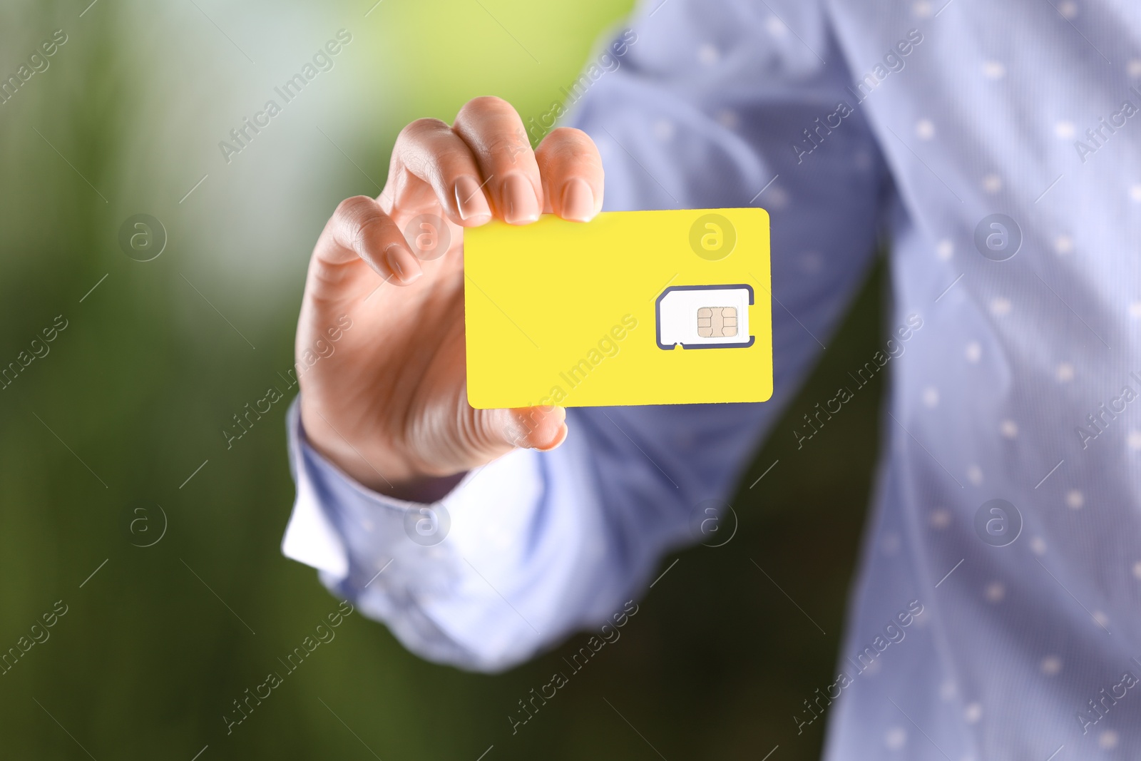 Photo of Woman holding SIM card on blurred background, closeup