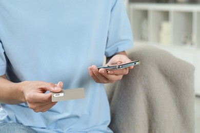 Man with SIM card and smartphone indoors, closeup