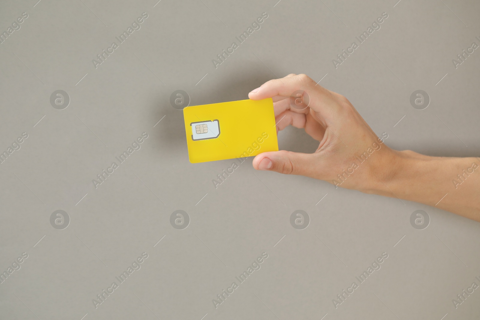 Photo of Man holding SIM card on grey background, closeup