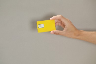 Photo of Man holding SIM card on grey background, closeup