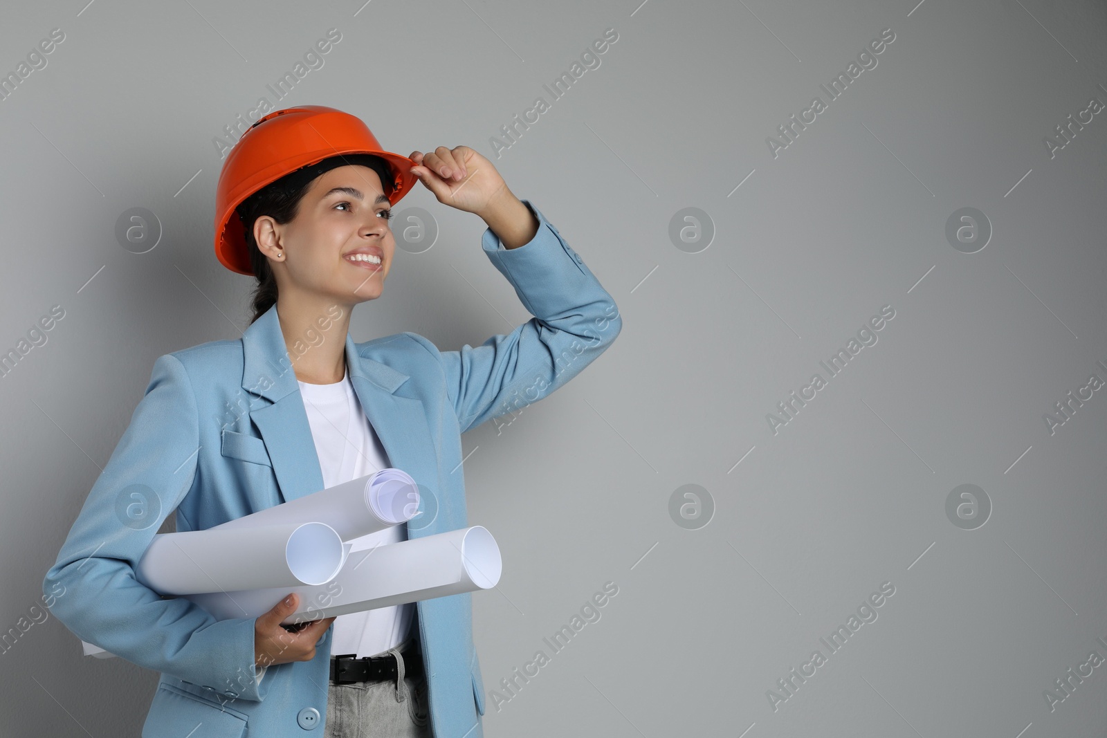 Photo of Engineer in hard hat with drafts on grey background, space for text