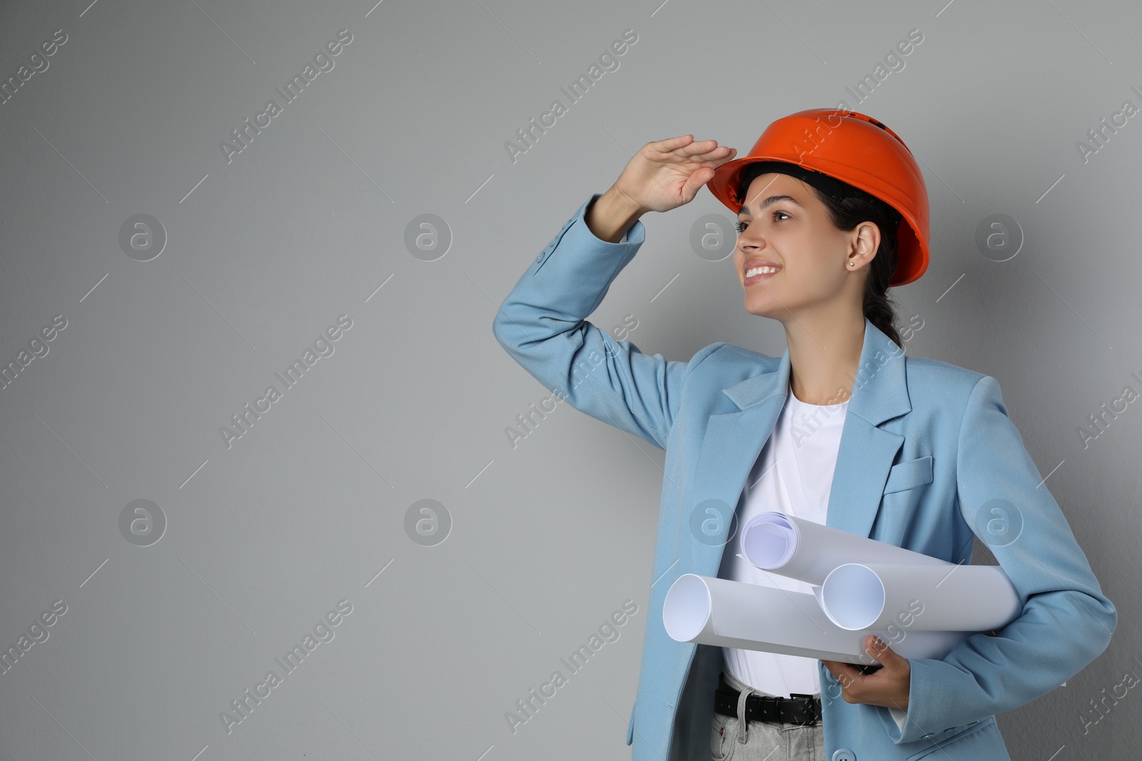 Photo of Engineer in hard hat with drafts on grey background, space for text