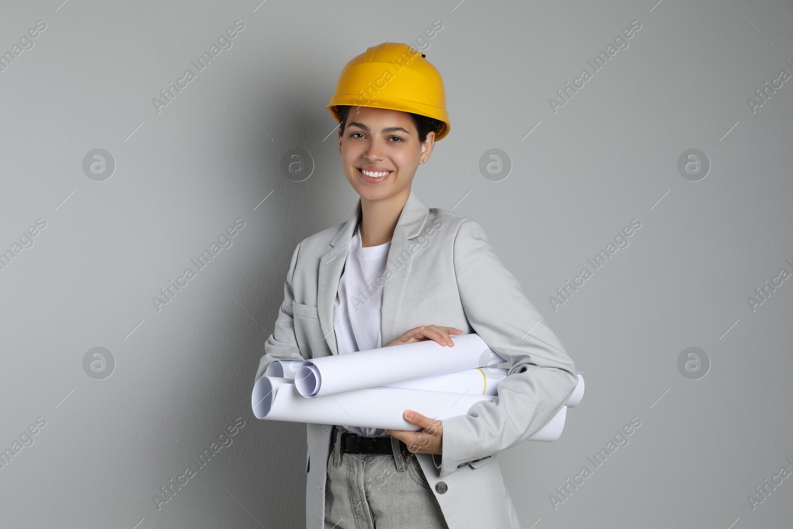 Photo of Engineer in hard hat with drafts on grey background