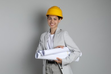 Photo of Engineer in hard hat with drafts on grey background