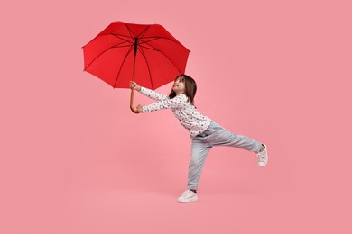 Photo of Cute little girl with red umbrella on pink background