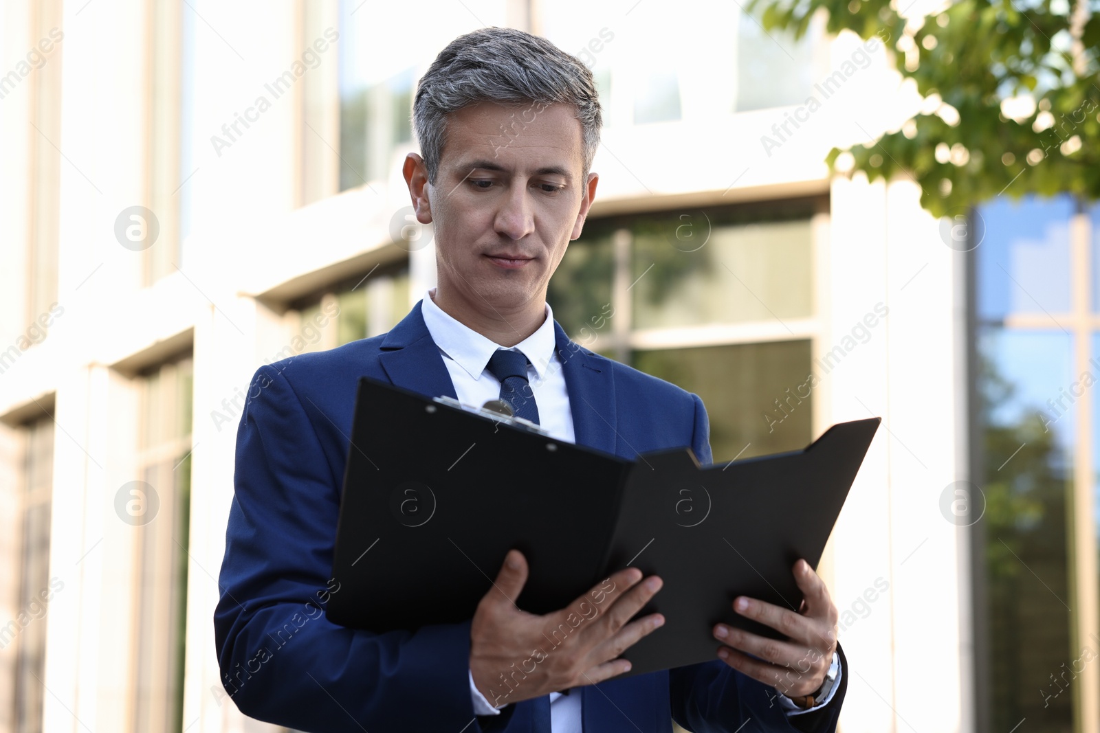 Photo of International relations. Diplomat with clipboard in suit outdoors