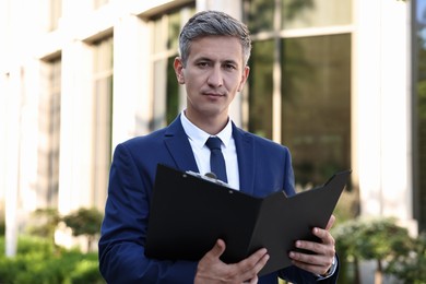 Photo of International relations. Diplomat with clipboard in suit outdoors