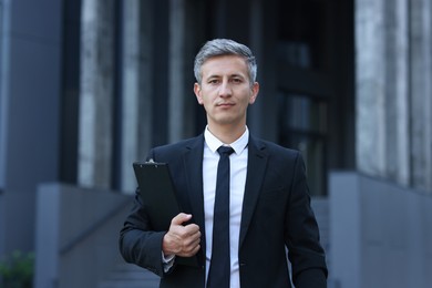 Photo of International relations. Diplomat with clipboard in suit outdoors