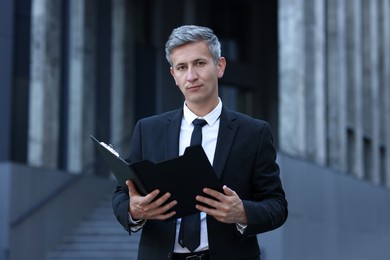 Photo of International relations. Diplomat with clipboard in suit outdoors