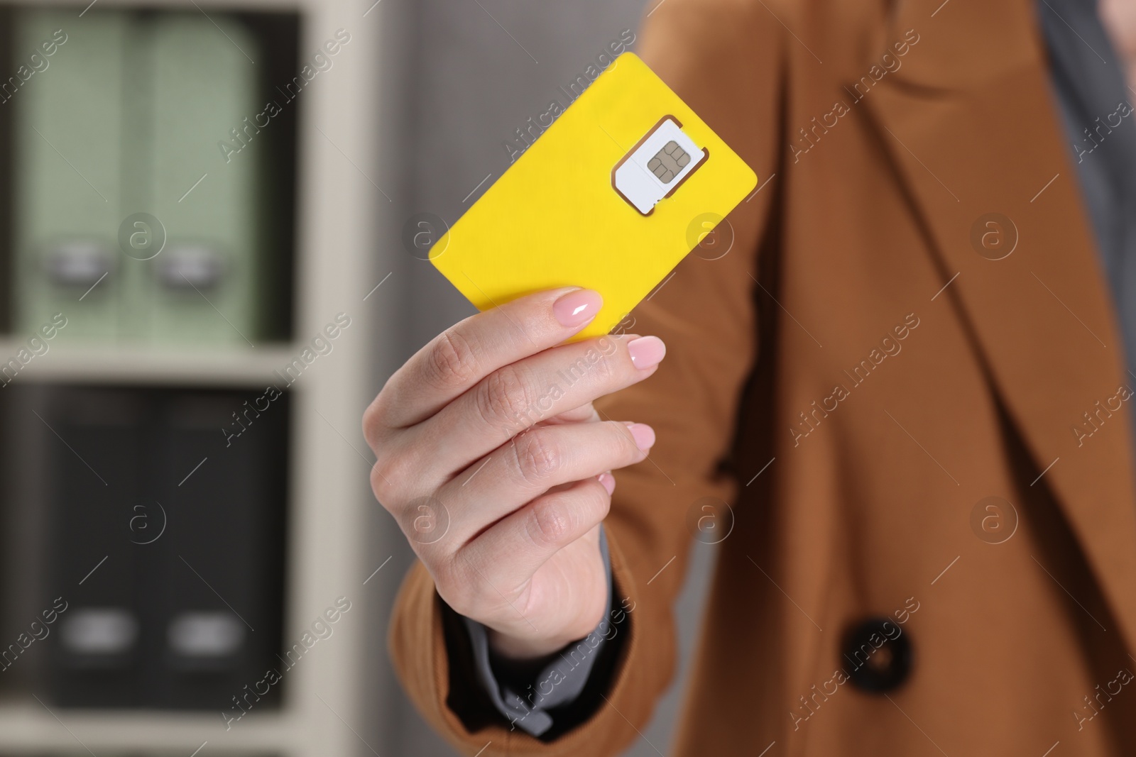 Photo of Woman holding SIM card indoors, closeup view