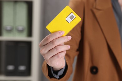 Photo of Woman holding SIM card indoors, closeup view