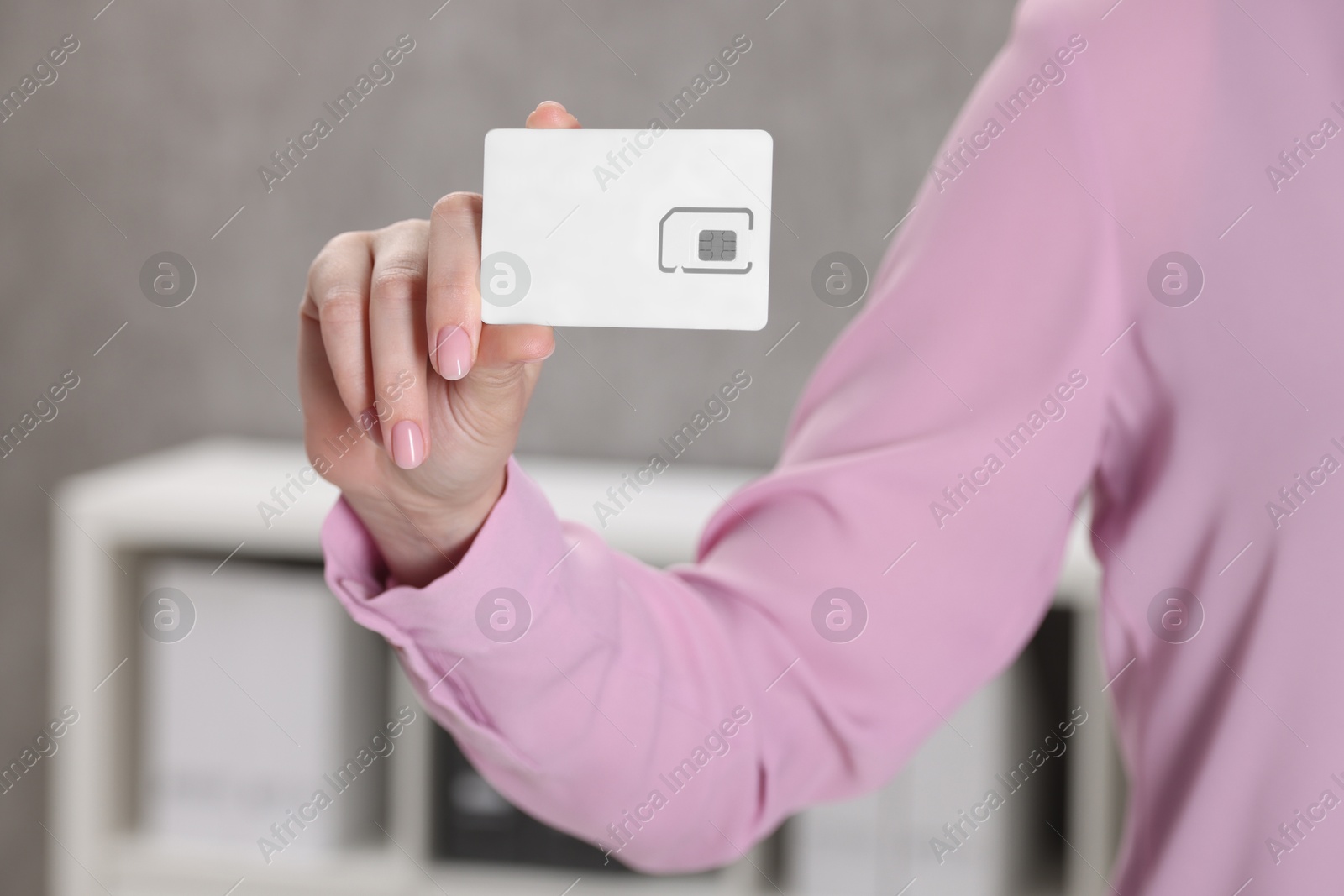 Photo of Woman holding SIM card indoors, closeup view