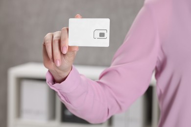 Photo of Woman holding SIM card indoors, closeup view