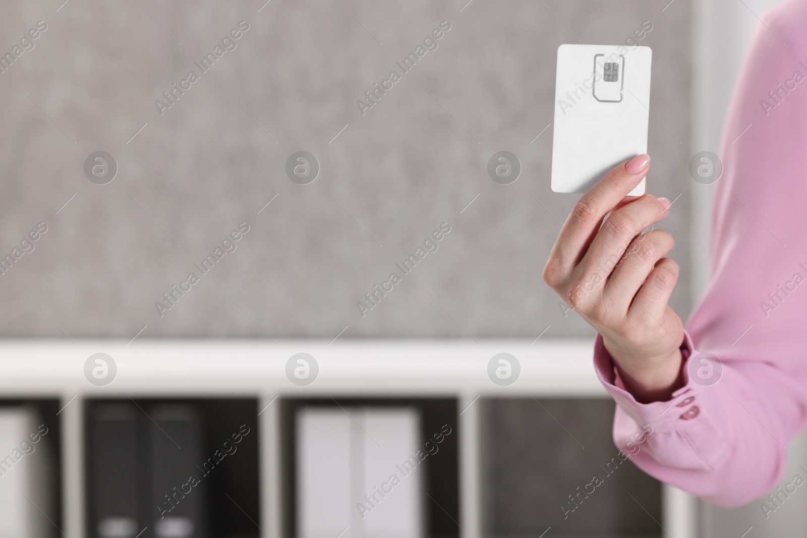 Photo of Woman holding SIM card indoors, closeup view. Space for text