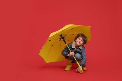 Little boy with yellow umbrella on red background