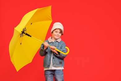 Little boy with yellow umbrella on red background, space for text