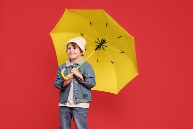 Little boy with yellow umbrella on red background