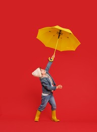 Photo of Little boy with yellow umbrella on red background, space for text